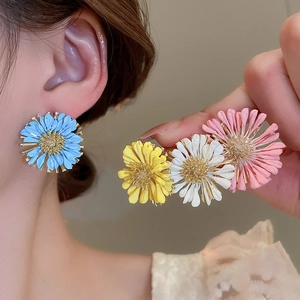 Detail of colorful daisy flower stud earrings in blue, yellow, white, and pink finishes