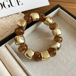 Detail of amber acrylic beads with gold foil and metallic cubes on jewelry tray