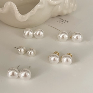 Elegant white pearl earrings with gold screw clips on decorative shell plate