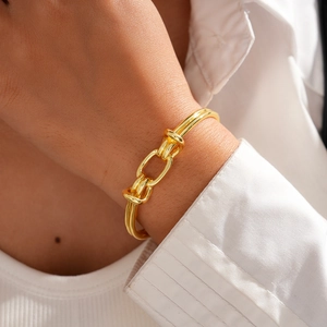 Close-up of a 18K gold plated knotted open bangle with a polished mirror finish