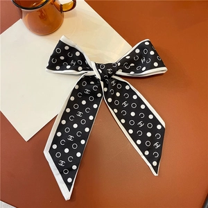 Dettaglio di un foulard in raso a pois annodato a fiocco su una scrivania elegante