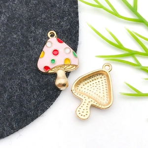 Detailed view of pink enamel mushroom charms with gold metal plating for DIY jewelry making