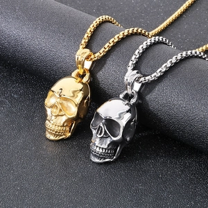 Close-up of gold and silver stainless steel skull pendants on matching box chains