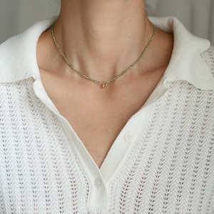 Close-up of olive green beaded necklace with gold and silver heart pendants on model