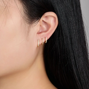 Three gold S925 silver hoop earrings with cubic zirconia on model's ear