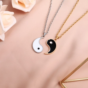 Detail of Yin Yang matching necklaces with black and white enamel on silk background
