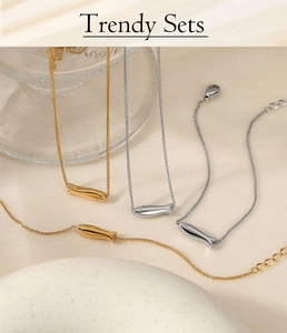 Detailed view of gold and silver fish-shaped necklace sets on glass display