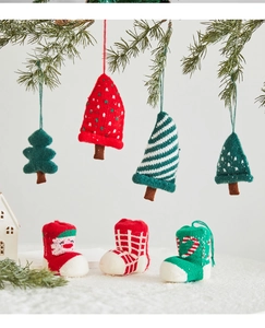 Detail of handmade knitted Christmas tree ornaments and mini stockings on pine branches