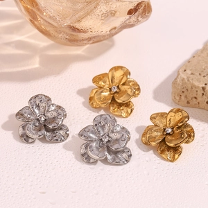 Detailed macro view of 18K gold and silver double-layered flower earrings with crystals