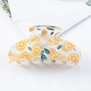 Detail of transparent acrylic hair claw featuring printed lemon slices and green leaves