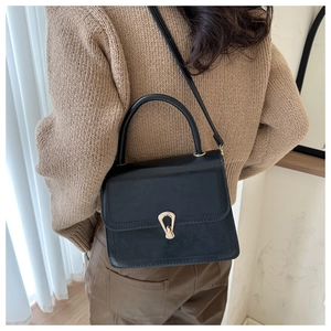 Close-up of a vintage black PU leather handbag with a prominent golden metal lock buckle
