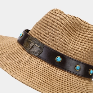 Detail of western straw hat with leather band featuring bull skull and turquoise studs