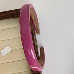 Detail of a thick fuchsia glossy headband with brown non-slip velvet inner lining
