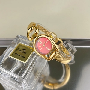 Close-up of gold-plated chain bracelet watch with vibrant red dial and Roman numerals