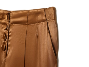 Close-up of brown satin wide-leg pants showing high waist with fabric-covered buttons