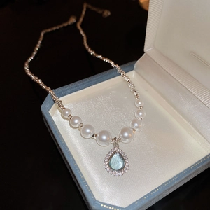 Macro detail of teardrop blue stone pendant with halo diamonds and white pearls