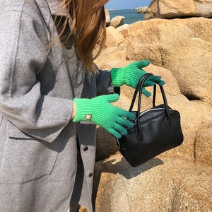 Detail of green ribbed knit gloves with touch screen feature on outdoor beach setting