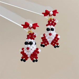 Detail of handmade beaded Santa Claus earrings with a red bow and white pearl accents