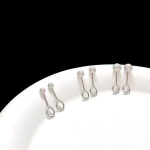Detailed view of three pairs of silver frosted ball stud earrings on white ceramic tray