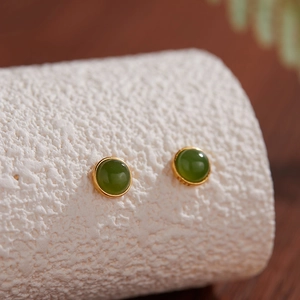 Macro de boucles d'oreilles en argent S925 avec jade vert sur surface texturée