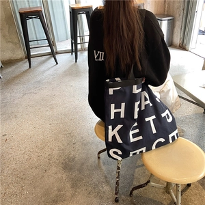 Detail of large canvas tote bag with white letter logo print and thick navy fabric