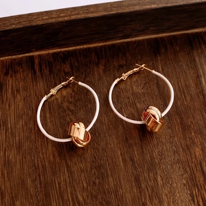 Detailed macro view of white circular hoop earrings with twisted gold-plated metal accents