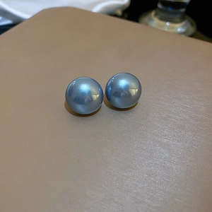 Macro shot of elegant blue round pearl earrings with a high-gloss finish and silver needles