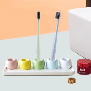 Minimalist ceramic toothbrush holder set with colorful bases and white tray organizer