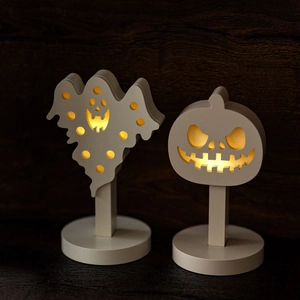 Halloween ghost and pumpkin silhouette LED lamps with warm yellow light on wood background