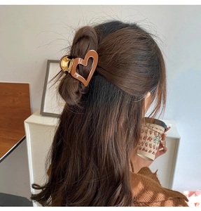 Pince à cheveux cœur marron en acétate sur une coiffure demi-attachée de femme