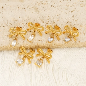 Boucles d'oreilles nœuds dorés avec zircons variés sur pierre et tissu frangé