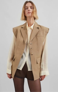 Dettaglio del gilet senza maniche color cammello con spalle larghe e revers classici