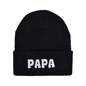 Detail of the white bouclé embroidered PAPA letters on a black knitted beanie hat