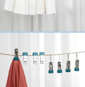 Detail of stainless steel clothes pegs with blue non-slip pads holding fabrics on a line