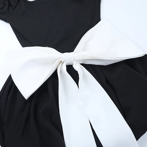 Détail d'un grand nœud blanc à la taille d'une robe noire chic à col carré
