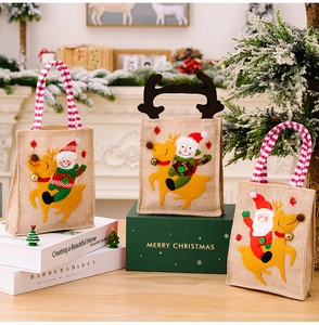 Detail of linen Christmas gift bags with Santa and snowman embroidery near a fireplace