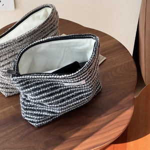 Close-up of thick tweed toiletry bags with black zippers and Simple Wish woven labels