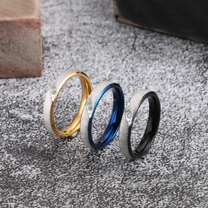 Detail of brushed stainless steel rings in gold, blue, and black with zircon inlay