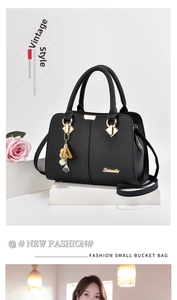 Détail du sac à main en cuir noir grainé avec logo doré et pendentif fleur