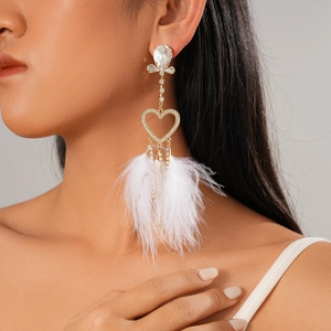 Detail of long heart earrings with white feathers, tassels, and sparkling rhinestones