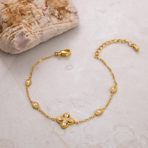 Detailed view of a golden four-leaf flower bracelet with white zircon and lobster clasp