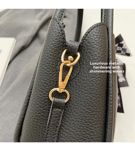 Detail of high-quality gold metal hook and D-ring on black lychee pattern leather bucket bag