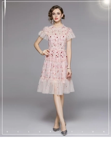 Vue détaillée d'une robe en tulle rose avec broderies florales rouges et volants étagés