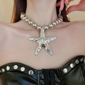Detail of oversized metallic starfish pendant on chunky silver bead choker necklace