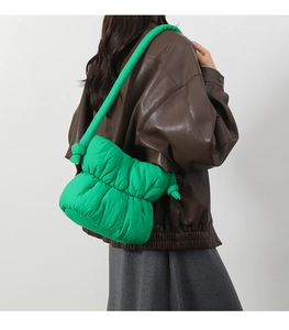 Detail of green puffy nylon bucket bag with quilted texture on female model shoulder