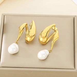 Détail de boucles d'oreilles dorées en V avec perles baroques et design ethnique