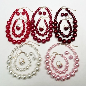 Flat lay of elegant pearl jewelry sets in red, white, and pink with necklace and earrings