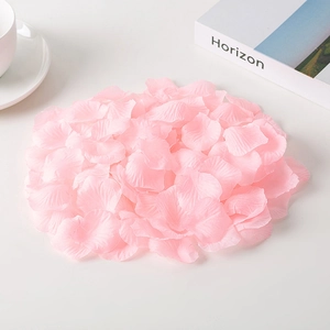 Pink artificial rose petals on white desk with a coffee cup for wedding decor