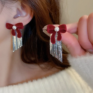 Dettaglio orecchini a fiocco in velluto rosso con perla e lunghe nappe di frange argento
