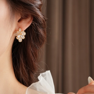 Detail view of sparkling zircon flower earrings worn by a model in a warm setting